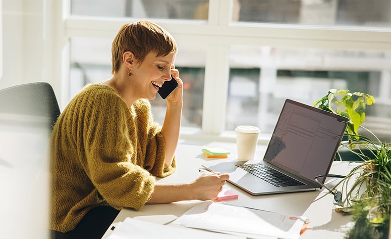 Happy Business Woman talking on phone taking notes in office-1